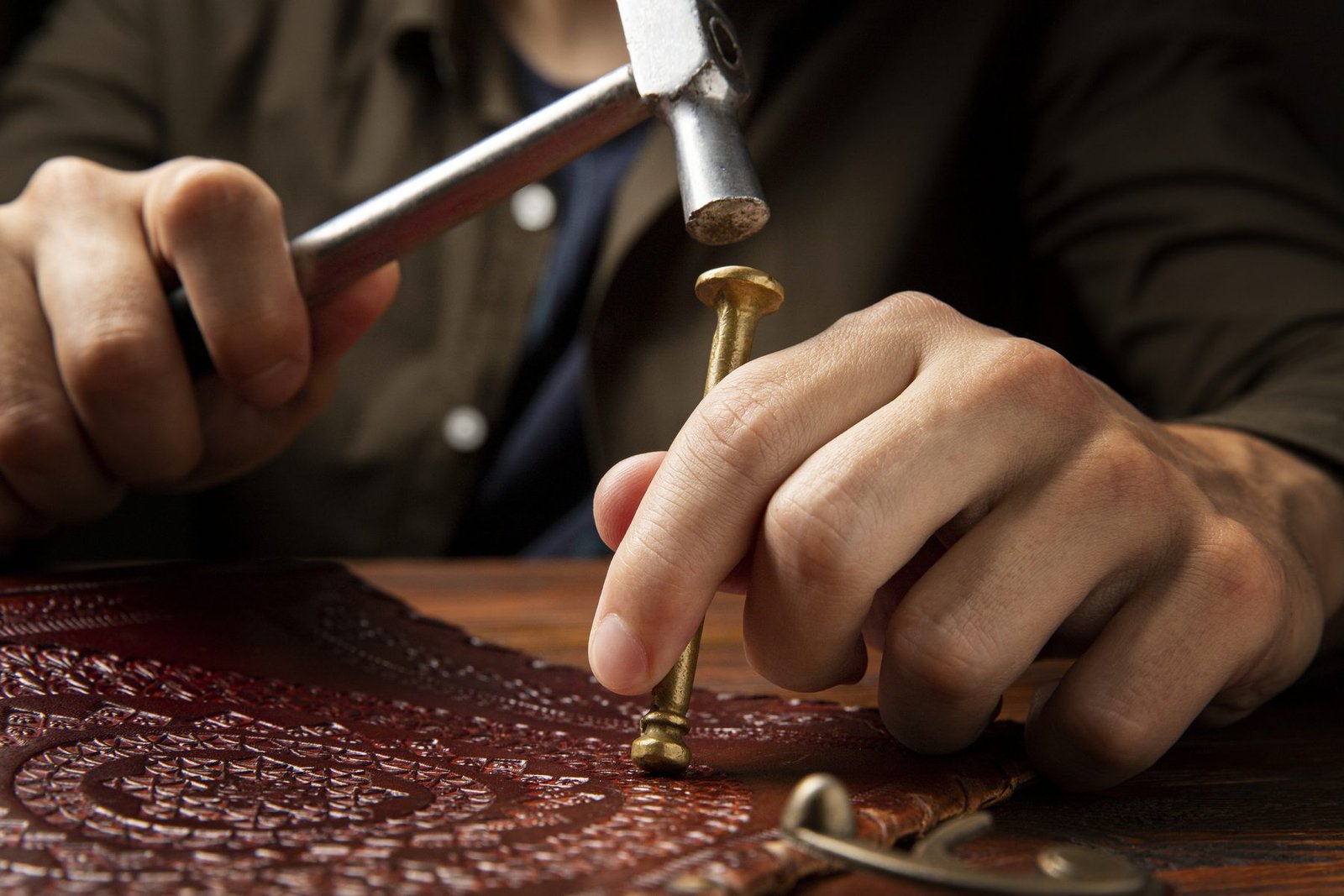 Artisan posant une rivure en laiton sur du cuir de vache gaufré à la main